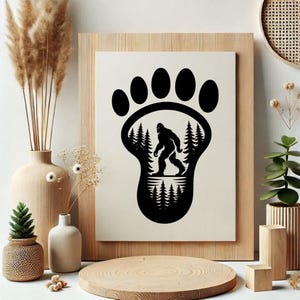 May include: Black and white Bigfoot print. The design features a large footprint with a silhouette of Bigfoot walking through a forest. The print is set in a wooden frame and is a unique piece of wall art.