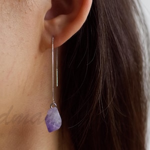 Peut inclure: Boucles d'oreilles pendantes en améthyste avec une chaîne en argent. Les boucles d'oreilles sont longues et délicates.