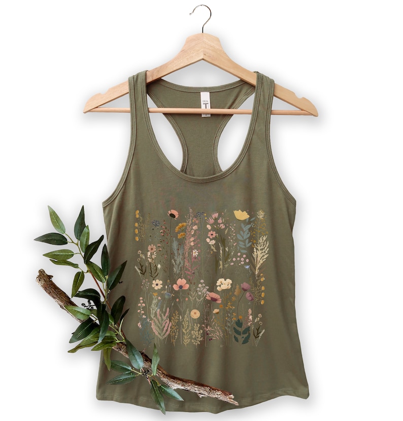 May include: A green tank top with a floral print featuring a variety of flowers and leaves in shades of pink, yellow, and green.