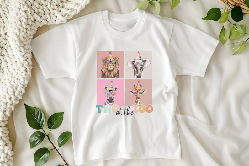 Op de afbeelding: Wit T-shirt met een afbeelding van vier dieren die feestmutsen en zonnebrillen dragen. De tekst "Two at the Zoo" is onder de dieren gedrukt.