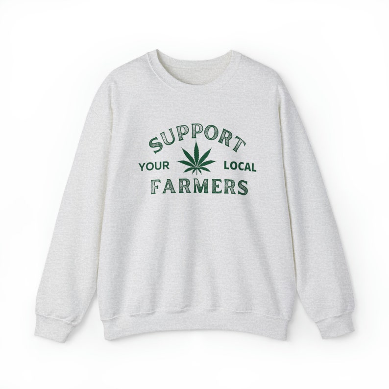 Puede incluir: Una sudadera gris jaspeada con un gr&aacute;fico de hoja de marihuana verde y el texto "Support Your Local Farmers".