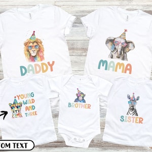May include: Set of five white t-shirts with colorful animal illustrations and text. The shirts feature a lion, elephant, cheetah, monkey, and zebra wearing party hats and sunglasses. The text on the shirts reads "Daddy", "Mama", "Young Wild and Three", "Brother", and "Sister".