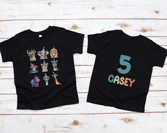 May include: Two black t-shirts. One shirt has a graphic of animals wearing party hats. The other shirt has the number 5 and the name Casey in colorful letters.