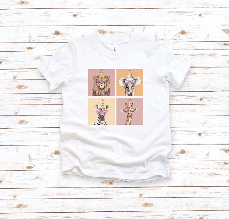 Pu&ograve; includere: Maglietta bianca con una grafica di quattro animali che indossano cappelli da festa e occhiali da sole. Gli animali sono un leone, un elefante, una zebra e una giraffa.