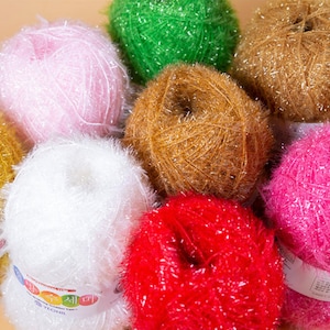 May include: A collection of colorful yarn balls with a sparkly, fuzzy texture. The yarn is arranged in a circle with the labels facing outward. The labels are in Korean and English.