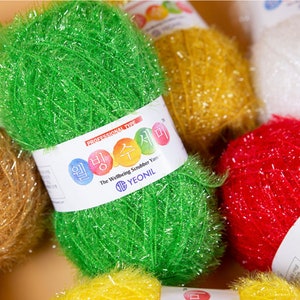 May include: Assortment of colorful scrubbing yarn balls. The yarn is made of a textured material and is designed for cleaning. The label reads "The Wellbeing Scrubber Yarn YEONIL".