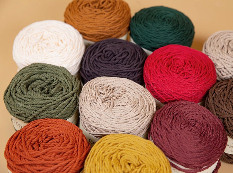 Puede incluir: Una colecci&oacute;n de ovillos de lana coloridos en varios tonos, incluyendo blanco, marr&oacute;n, verde, rojo y amarillo. La lana est&aacute; bien enrollada, lo que sugiere que es adecuada para proyectos de tejido o ganchillo. La imagen est&aacute; bien iluminada, mostrando la textura y los colores.