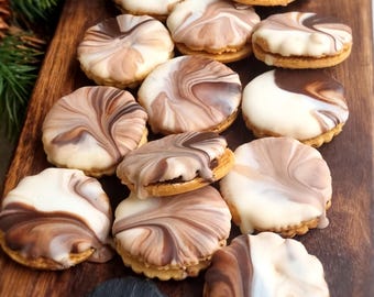 Peut inclure: Vue aérienne de plusieurs biscuits ronds glacés avec un glaçage marbré blanc et marron. Les biscuits sont disposés sur une surface en bois foncé. Certains biscuits sont garnis d'une garniture. Une petite ardoise avec le chiffre "2009" est au premier plan.