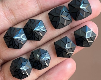 May include: Eight black faceted gemstone cabochons in a starburst shape. The gemstones are displayed on a hand.
