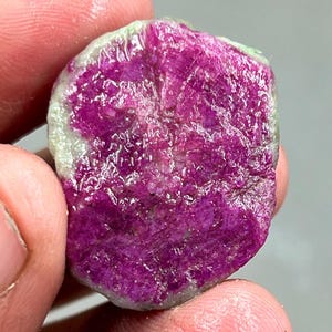 Könnte beinhalten: Nahaufnahme eines rosa-grünen Edelsteins. Der Edelstein hat eine raue, natürliche Textur und ist unregelmäßig geformt.