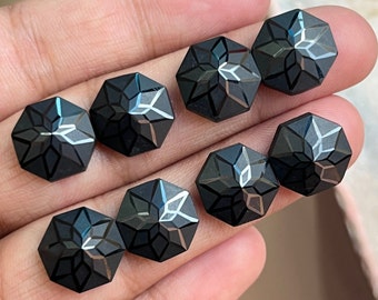 May include: Eight black faceted gemstone cabochons with a star-shaped design. The cabochons are hexagonal in shape and have a glossy finish.