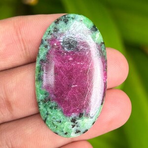 Könnte beinhalten: Ovaler, grüner und rosafarbener Edelstein-Cabochon mit einer glatten, polierten Oberfläche. Der Stein hat ein einzigartiges Muster aus grünen und rosafarbenen Farben mit einem Hauch von Weiß.