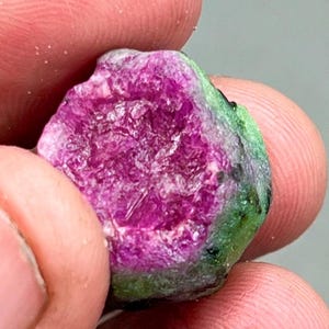 Peut inclure: Gros plan sur une pierre précieuse rose et verte. La pierre précieuse a une texture rugueuse et naturelle et une forme irrégulière.
