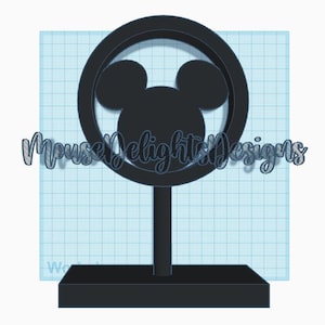 Peut inclure: Silhouette noire de la tête de Mickey Mouse à l'intérieur d'un cercle noir sur un socle noir. Le socle a une base carrée.