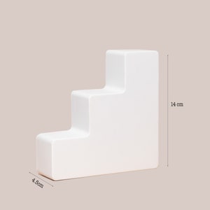Op de afbeelding: Een witte drietraps displaystandaard met een rechthoekige basis, 4,8 cm breed en 14 cm hoog. De standaard is gemaakt van een glad, wit materiaal en is perfect voor het presenteren van kleine items.