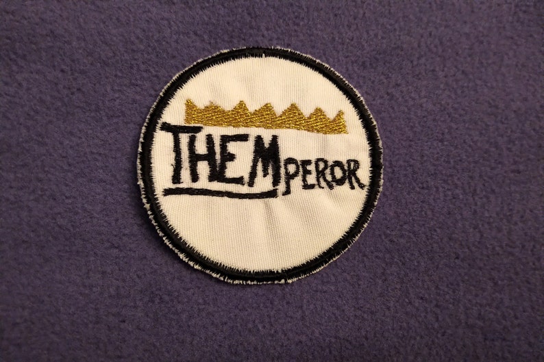 May include: A white embroidered patch with a black outline and a gold crown above the text "THEMPEROR".