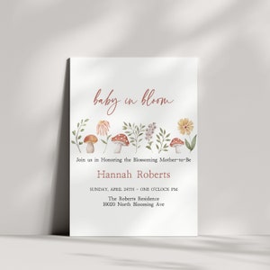 Puede incluir: Una invitación a una fiesta de bienvenida al bebé con una ilustración de acuarela de hongos y flores. El texto dice "baby in bloom" e incluye el nombre "Hannah Roberts", la fecha "domingo 24 de abril", la hora "una en punto de la tarde", la ubicación "The Roberts Residence" y la dirección "10020 North Blooming Ave".