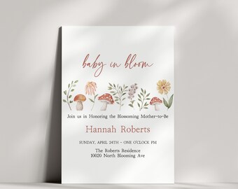 Può includere: Un invito a un baby shower con un'illustrazione ad acquerello di funghi e fiori. Il testo recita "baby in bloom" e include il nome "Hannah Roberts", la data "domenica 24 aprile", l'ora "un'ora del pomeriggio", la location "The Roberts Residence" e l'indirizzo "10020 North Blooming Ave".