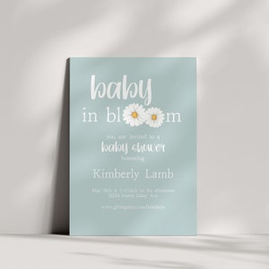 Puede incluir: Una invitaci&oacute;n de color azul claro para un baby shower con texto blanco que dice "baby in bloom" con dos margaritas blancas con centros amarillos. La invitaci&oacute;n tambi&eacute;n incluye el texto "est&aacute;s invitado a un baby shower en honor a Kimberly Lamb" y la fecha, hora y lugar del baby shower. La invitaci&oacute;n tambi&eacute;n incluye una direcci&oacute;n de sitio web para el registro de regalos.
