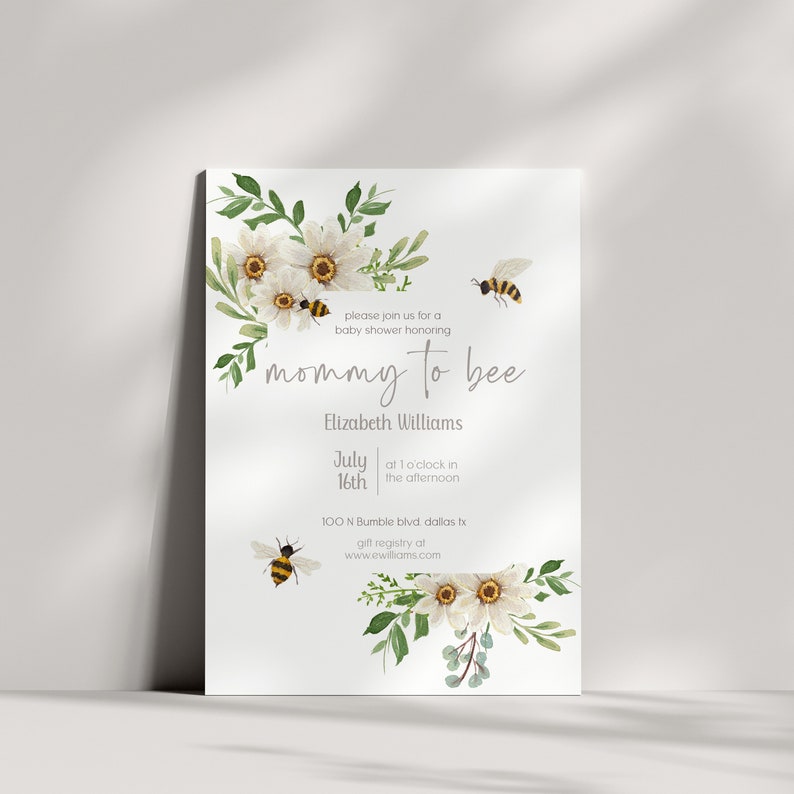 Puede incluir: Una invitaci&oacute;n de baby shower floral blanca y verde con el texto "mommy to bee" y el nombre "Elizabeth Williams". La invitaci&oacute;n incluye la fecha "July 16th" y la hora "at 1 o'clock in the afternoon". La ubicaci&oacute;n es "100 N Bumble blvd dallas tx". La invitaci&oacute;n tambi&eacute;n incluye una direcci&oacute;n de sitio web para el registro de regalos.