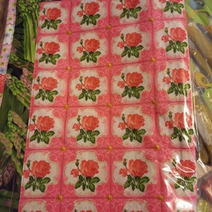 May include: A pink fabric panel with a repeating pattern of pink roses in white and green frames. The fabric is quilted and has a green and white border.