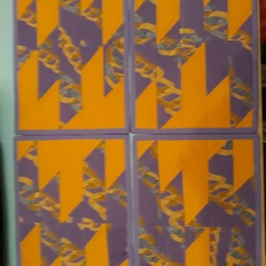 May include: Four placemats with a geometric pattern of purple and orange. The pattern is made up of overlapping triangles and rectangles.