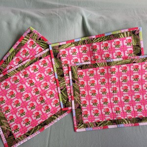 May include: Four pink and green quilted placemats with a floral pattern. The placemats have a multi-coloured trim.