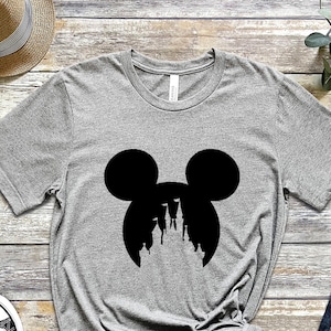 May include: A gray t-shirt with a black silhouette of Mickey Mouse's head with the silhouette of Cinderella's castle inside the ears.