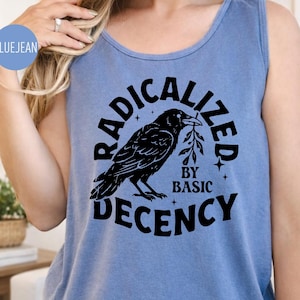 May include: A light blue tank top with a black graphic of a raven holding a sprig and the words "RADICALIZED BY BASIC DECENCY". The tank top is made of a soft material and has a scoop neck.