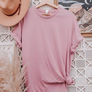 May include: A plain, dusty rose colored t-shirt with rolled up sleeves. The t-shirt is made of a soft, comfortable material.