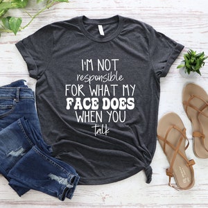 May include: A dark gray t-shirt with white text that reads "I'm not responsible for what my face does when you talk".