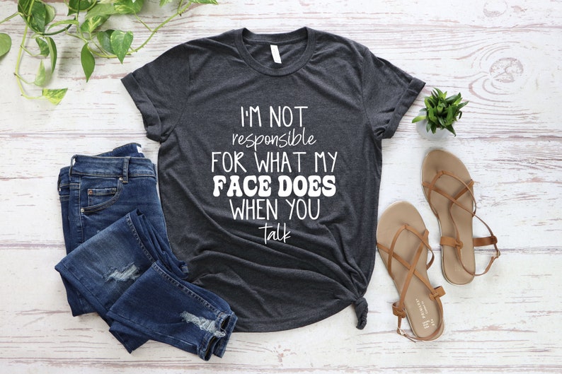 May include: A dark gray t-shirt with white text that reads "I'm not responsible for what my face does when you talk".