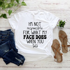May include: White t-shirt with black text that reads "I'm not responsible for what my face does when you talk".
