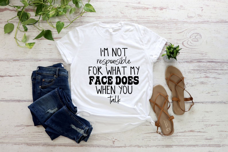 May include: White t-shirt with black text that reads "I'm not responsible for what my face does when you talk".
