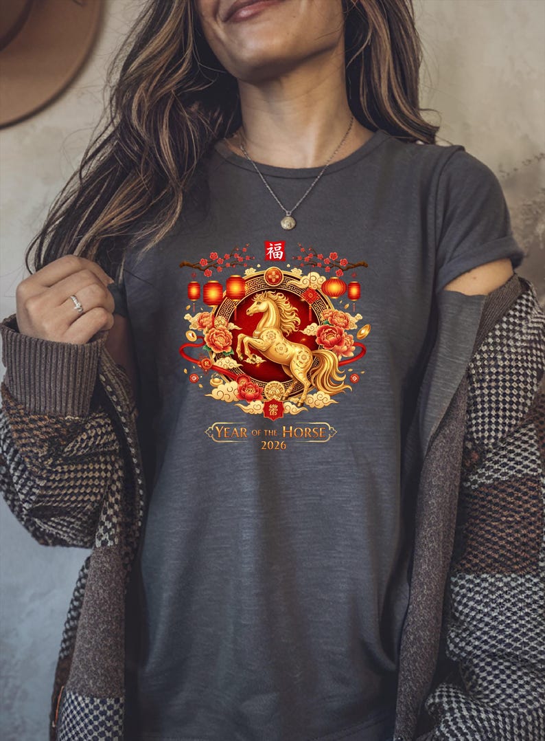 May include: Dark gray t-shirt featuring a golden horse design within a circular frame. The design includes red lanterns, flowers, and the text "Year of the Horse 2026". The shirt has short sleeves.