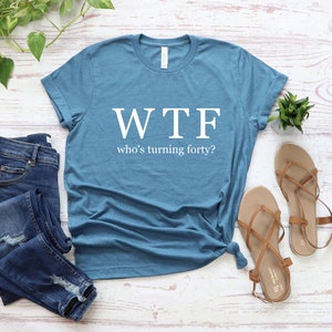 K&ouml;nnte beinhalten: Ein blaues T-Shirt mit dem Aufdruck "WTF who's turning forty?" in wei&szlig;.