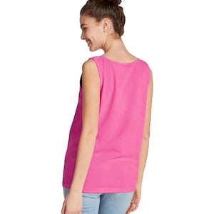 Puede incluir: Una camiseta sin mangas de color rosa intenso liso, con un cuello redondo ancho y un dobladillo recto. La prenda est&aacute; confeccionada con un tejido liso y opaco, y presenta un dise&ntilde;o sencillo y limpio sin patrones, logotipos ni adornos visibles.