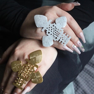 May include: Two large, ornate rings with intricate designs. One ring is silver and the other is gold.