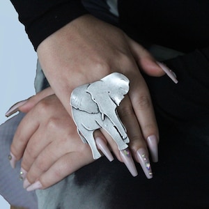 Puede incluir: Un anillo de plata con un dise&ntilde;o de elefante detallado. El anillo se lleva en un dedo.