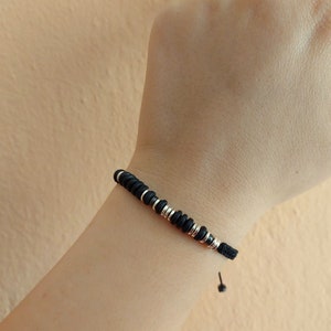Könnte beinhalten: Ein schwarzes und silbernes Armband mit Perlen und einem Kordelverschluss.