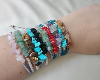 Puede incluir: Una pila de pulseras de piedras preciosas de colores con varias piedras, incluyendo turquesa, coral rojo, jade verde y ojo de tigre.