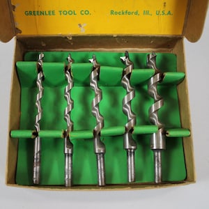 Op de afbeelding: Een set van zes boortjes in een kartonnen doos met een groene binnenkant. De doos is gelabeld "GREENLEE TOOL CO. Rockford, Ill., U.S.A."