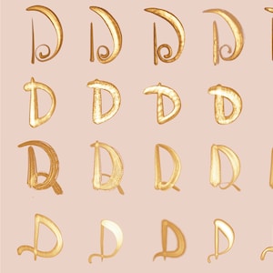 May include: Twenty-five variations of the letter 'D' in a gold metallic font on a light pink background.