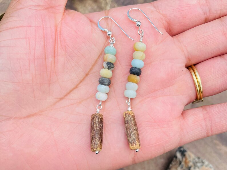 Peut inclure: Boucles d'oreilles faites &agrave; la main avec un m&eacute;lange de perles rondes color&eacute;es dans les tons de bleu, jaune et gris, enfil&eacute;es sur du fil d'argent. Les boucles d'oreilles sont finies avec une petite perle en bois cylindrique en bas.