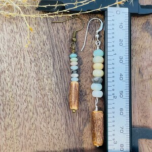 Peut inclure: Boucles d'oreilles faites &agrave; la main avec des perles de pierres naturelles bleues, cr&egrave;me et grises, et un &eacute;l&eacute;ment en bois. Les boucles d'oreilles mesurent environ 7.6 cm de long, de style boh&egrave;me rustique.