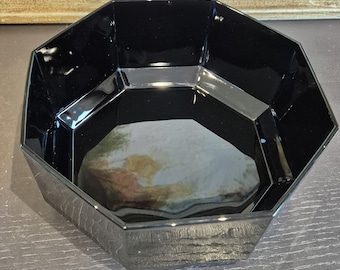 May include: A glossy black octagonal bowl with a smooth, reflective surface and defined geometric edges. The interior of the bowl is deep and dark, showcasing a wide opening that tapers down to a flat base, creating a clean and functional design.