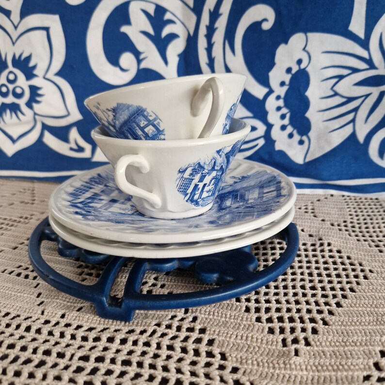 K&ouml;nnte beinhalten: Zwei blaue und wei&szlig;e Teetassen mit einem Blumenmuster auf einer blauen und wei&szlig;en Untertasse. Die Tassen und die Untertasse stehen auf einem blauen und wei&szlig;en Untersetzer.