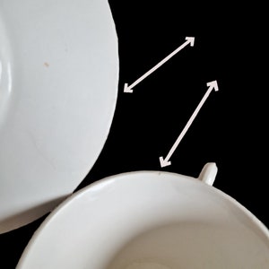 K&ouml;nnte beinhalten: Ein wei&szlig;es Porzellan-Teetassen- und Untertassen-Set. Die Untertasse ist etwas gr&ouml;&szlig;er als die Teetasse und hat einen leicht erh&ouml;hten Rand. Die Teetasse hat einen kleinen Henkel an der Seite.