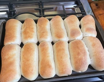 May include: A baking tray filled with 12 golden brown bread rolls, freshly baked and ready to be served.