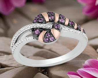 May include: A silver and rose gold ring with a swirl design featuring purple and black gemstones.